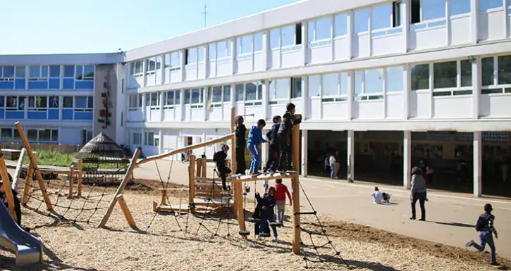 La cour de l'école des Chataigniers, à Nantes. Au premier plan, des enfants s'amusent dans des structures en bois.