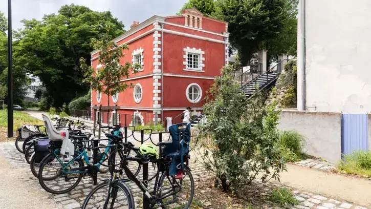 Des vélos devant la façade rouge de la Maison de l'apiculture, à Nantes.