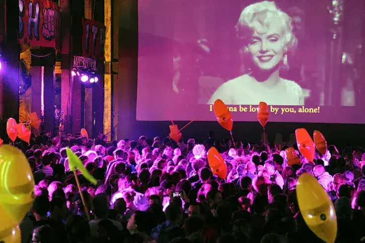 Une foule regarde la projection d'un film en chantant