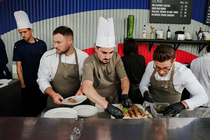 Des cuisiniers s'affairent autour d'un plat. 