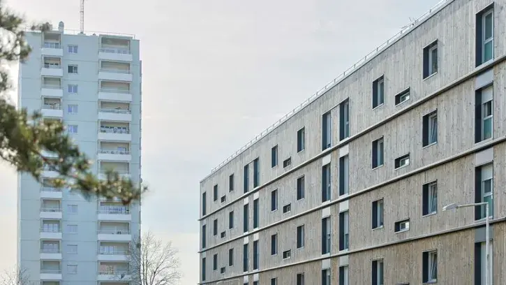 Des façades d'immeubles rénovés, l'une en bois, l'autre équipée de loggias.
