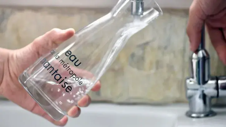 Un habitant de la Métropole remplit une carafe d'eau au robinet