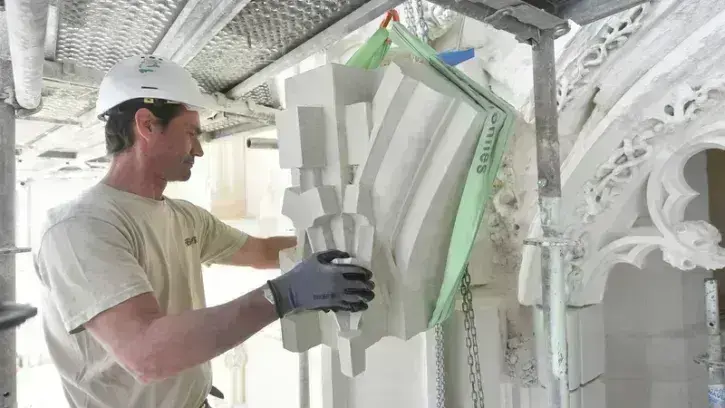 David Mistour est chef de chantier. Il vérifie ici le positionnement d'un bloc de tuffeau, soulevé à bonne hauteur grâce à un palan.