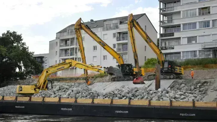 Michel Mohier, conducteur d'engins embarqué à bord du ponton, dépose les enrochements sur la berge, tandis que les deux pelles équipées de GPS, positionnent les roches pour que le talus prenne forme correctement. © Rodolphe Delaroque