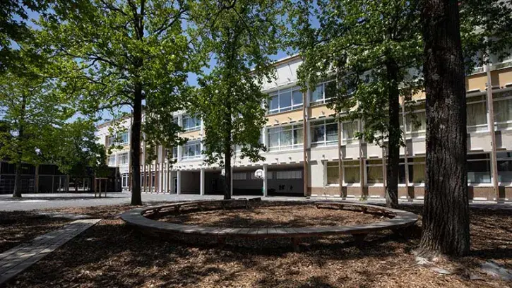 Côté maternelle, la cour est séparée en deux zones. D'un côté, la cour nature avec tables et chaises dans l'herbe. De l'autre, une cour avec des structures de jeux existantes.